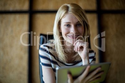 Young woman holding digital tablet smiling at camera