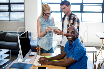 Man working on computer while interacting in the background