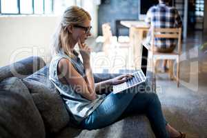 Young woman sitting on sofa using laptop