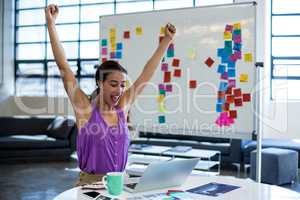 Excited woman sitting on table with digital tablet and laptop