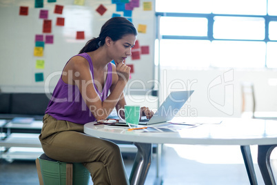 Young woman sitting at desk using laptop