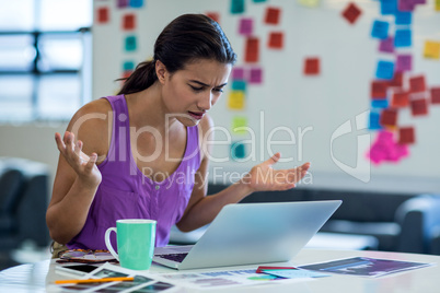 Young woman looking surprised while using the laptop