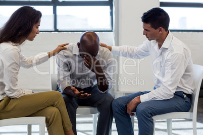 Colleagues comforting a unhappy man