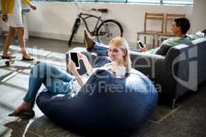 Young woman sitting on a bean bag holding digital tablet