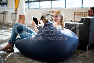 Young woman sitting on a bean bag holding digital tablet