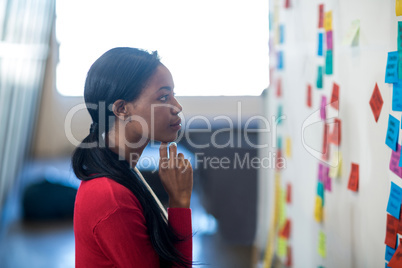 Young woman reading sticky notes on white board