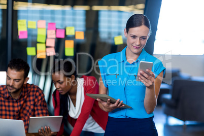 Young woman text messaging on mobile phone and holding digital t