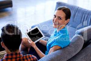 Young woman holding digital tablet sitting on sofa