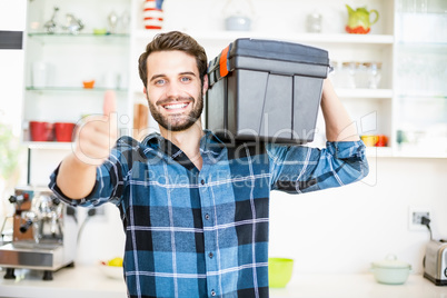 Man carrying tool box giving thumbs up