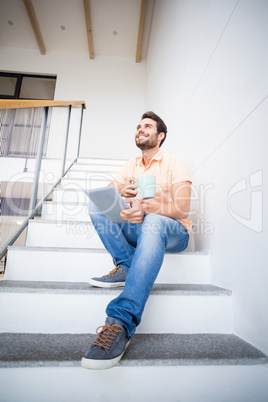 Man holding digital tablet and coffee mug