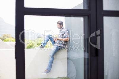 Man sitting on terrace using digital tablet