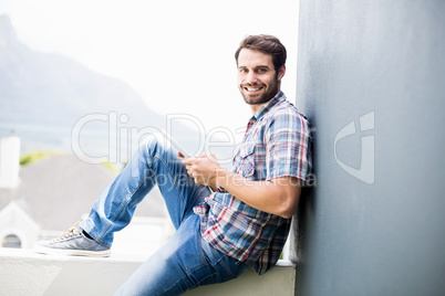 Man sitting on terrace holding digital tablet