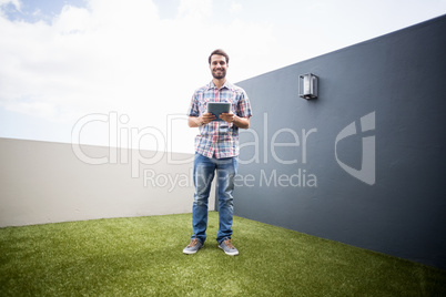 Man standing on terrace holding digital tablet