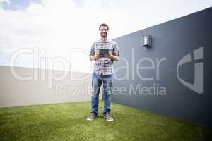 Man standing on terrace holding digital tablet