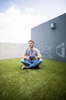 Man sitting on terrace holding digital tablet