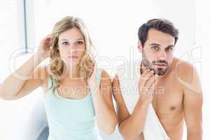 Man and woman checking their skin in bathroom