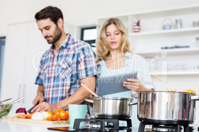 Young couple chopping vegetable and using digital tablet