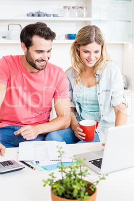 Young couple using laptop while checking a bills