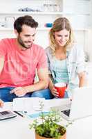 Young couple using laptop while checking a bills