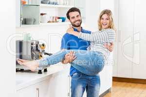 Man lifting woman in his arms in kitchen