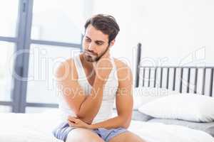 Tensed young man sitting on bed