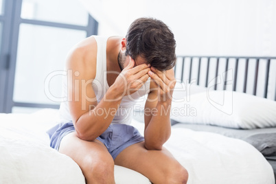 Tensed young man sitting on bed