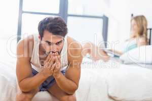 Tensed young man sitting on bed