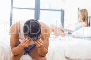 Tensed young man sitting on bed