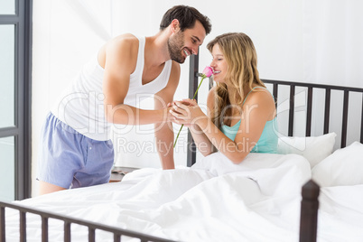 Young man offering a flower to woman