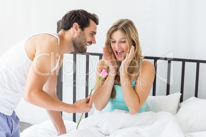 Young man offering a flower to woman