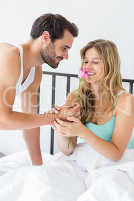 Young man offering a flower to woman