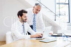 Businessmen discussing office work on laptop