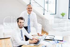 Businessmen discussing office work on laptop