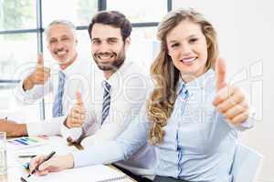 Business colleagues showing thumbs up in a meeting