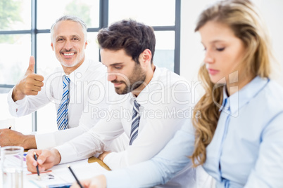 Businessman showing thumbs up in a meeting