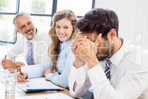 Smiling colleagues looking at frustrated businessman