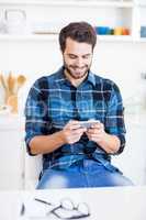 A man is smiling and looking at his smartphone