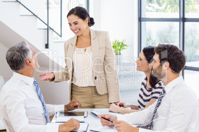 A businesswoman is talking to her colleagues who are listening t