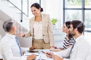 A businesswoman is talking to her colleagues who are listening t