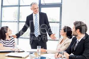 A businessman is talking to his colleagues and all are smiling