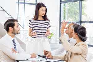 A woman is standing and looking at her colleagues