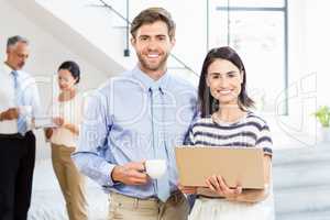 Businessman holding coffee cup and a colleague holding laptop