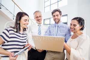 Smiling business people using laptop and tablet