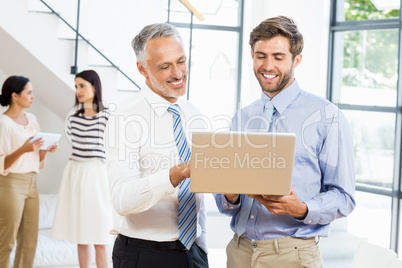 Businessmen interacting using laptop