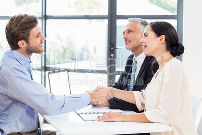 Businessman shaking hands with businesswoman in meeting