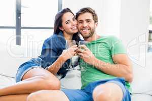 Portrait of young couple sitting on sofa with a glass of red win