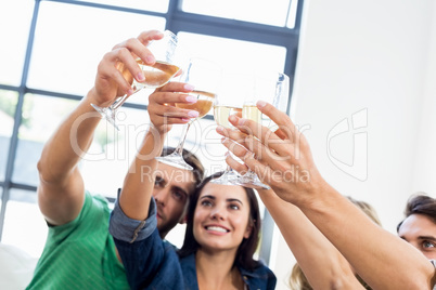 Smiling friends sitting on sofa clinking glasses