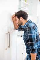 Depressed man leaning his head against a door