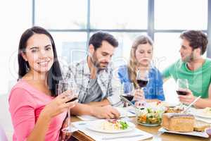 Portrait of woman holding wine glass having meal with friends