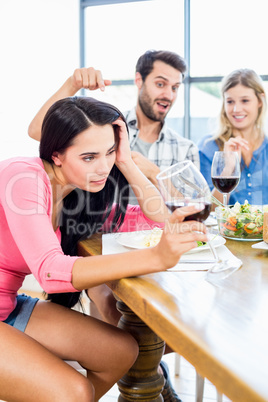 Friends looking drunk woman with wine glass